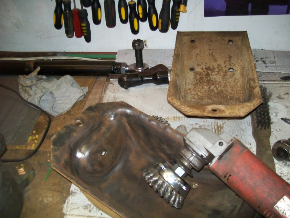 Angle grinder cleaning a rusty metal part on a workbench.