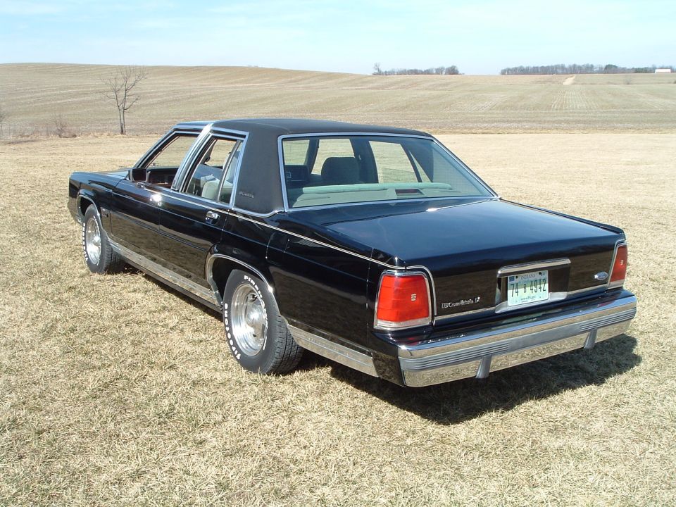 Rear three-quarter of black Ford LTD Crown Victoria sedan in a brown field