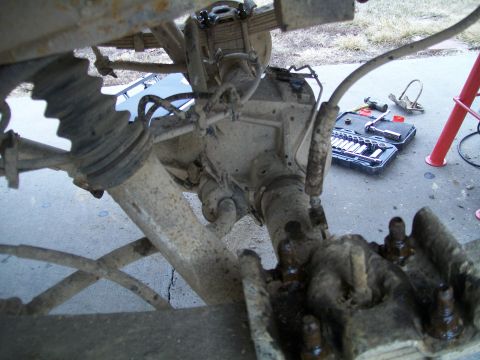 1991 Ford Bronco - The rear axle and suspension components of a vehicle are shown, with a toolbox and tools laid out on the ground nearby. This appears to be…