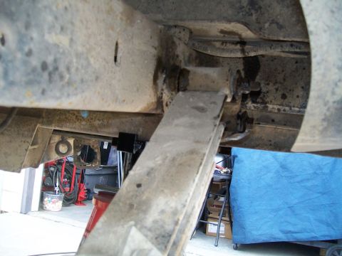 1991 Ford Bronco - A close-up, low-angle view of the undercarriage of a vehicle, focusing on the suspension system. A leaf spring is visible, attached to the…