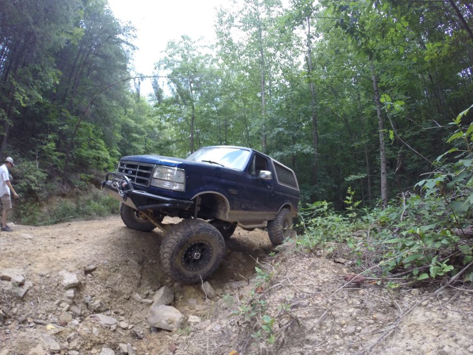 Dark blue Ford Bronco off-roading on a steep, rocky trail.