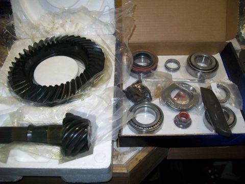 1991 Ford Bronco - A differential gear set and bearings are laid out in a box. The set includes a large ring gear and a smaller pinion gear with its shaft.