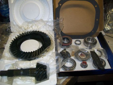 1991 Ford Bronco - A differential gear set and bearings are laid out in a box. The set includes a large ring gear, a smaller pinion gear, and various bearings…
