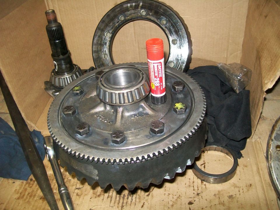 Differential gear assembly with pinion gear, bearings, and Loctite on cardboard.