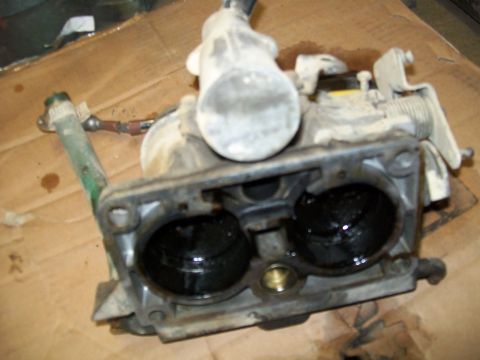 1991 Ford Bronco - A close-up view of a dirty carburetor, showing internal components and signs of wear.