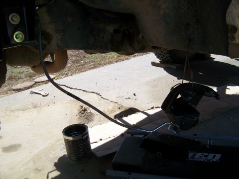 1991 Ford Bronco - Undercarriage view shows brake components and suspension parts, with a can and tools nearby.