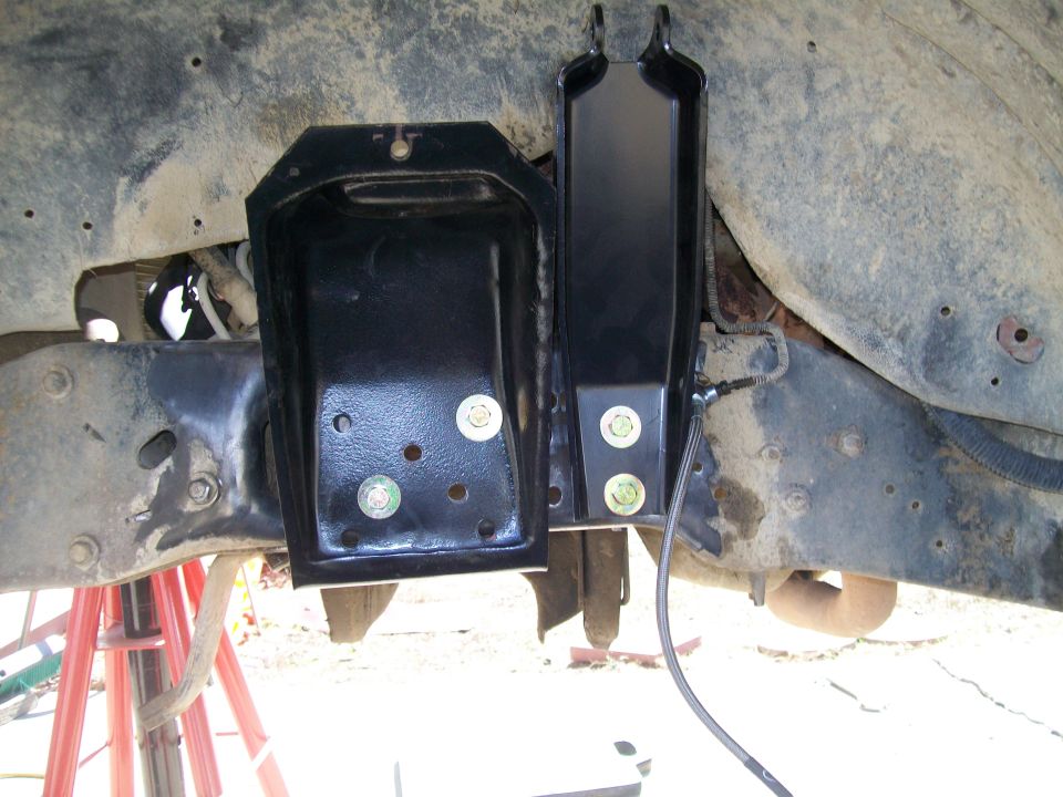Aftermarket suspension bracket bolted to vehicle frame with brake line attached