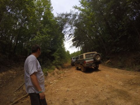 2016 Ford Bronco - A tan and green Ford Bronco with a spare tire on the back navigates a dirt road, followed by another vehicle.