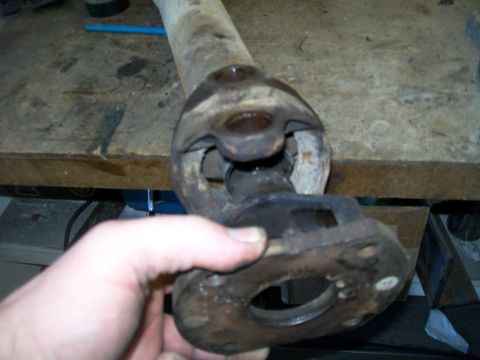 1991 Ford Bronco - Close-up of a worn driveshaft U-joint assembly being held.