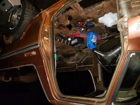 1979 Ford Bronco - The interior of a 1979 Ford Bronco shows significant rust and is filled with various parts and fluids.