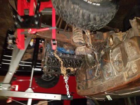 1979 Ford Bronco - The engine and undercarriage of a vehicle are visible as it is being worked on, likely undergoing maintenance or repair.