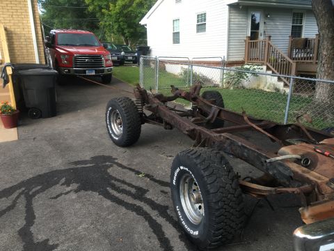 1979 Ford Bronco - A modern pickup truck tows a bare chassis, likely for restoration or parts.