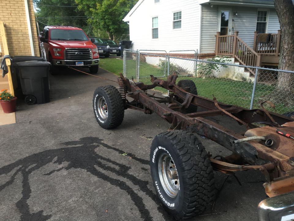 Red Ford F-150 towing a rusty vehicle frame with BFGoodrich tires