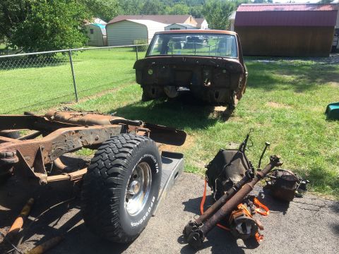 1979 Ford Bronco - Disassembled 1978 Ford Bronco body and chassis sit in a yard with drivetrain components nearby.