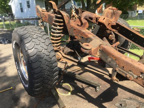 1979 Ford Bronco - A heavily rusted vehicle frame and suspension are visible, along with a large off-road tire.