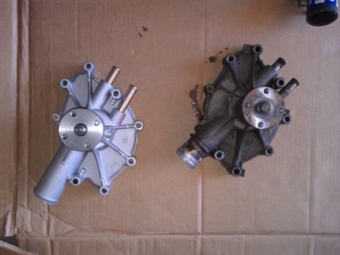 1996 Ford Bronco - Two water pumps, one new and one used, are laid out on a cardboard surface.