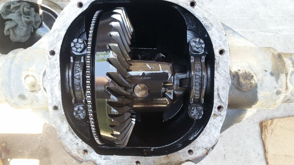 Open differential housing with gears visible. Some text is stamped on the housing