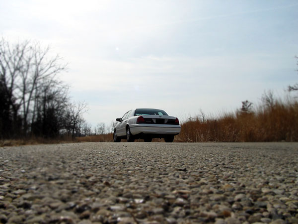 2000 Ford Crown Victoria parked on a gravel road with dry grass and trees in the background