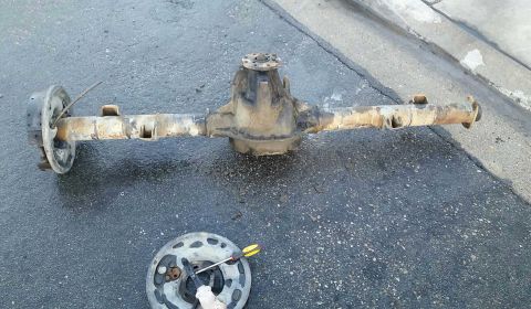 1992 Ford Bronco - Rear axle assembly, likely from a Ford Bronco, resting on asphalt.