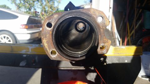1992 Ford Bronco - A rusty axle housing part is shown in the foreground with a white car in the background.