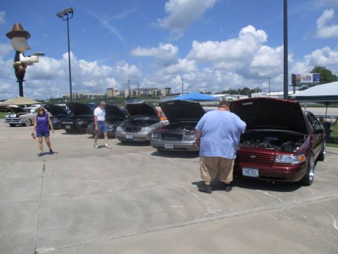 2004 Ford Crown Victoria - A red 2004 Ford Crown Victoria is displayed with its hood open at an outdoor car event.