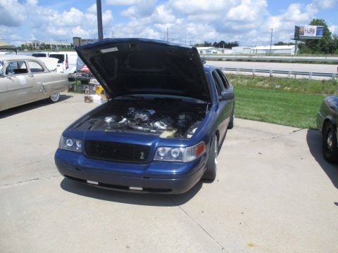2004 Ford Crown Victoria - A blue 2004 Ford Crown Victoria is parked outside with its hood open, revealing the engine.