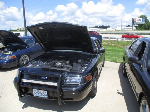 2004 Ford Crown Victoria - A black 2004 Ford Crown Victoria is parked with its hood open, alongside another vehicle.