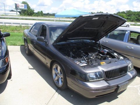 2004 Ford Crown Victoria - A dark gray 2004 Ford Crown Victoria is displayed with its hood open, revealing the engine compartment.
