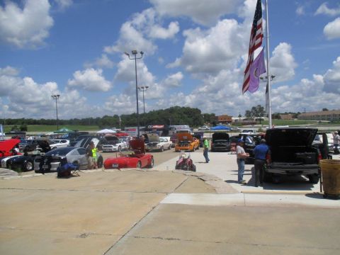 2004 Ford Crown Victoria - A variety of cars are parked and displayed at an outdoor event, with people milling around.