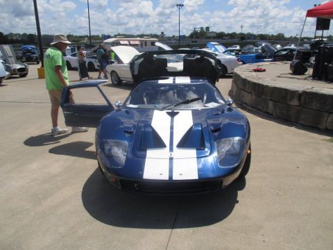 2004 Ford Crown Victoria - A blue and white Ford GT is parked with its door open at an outdoor car show.