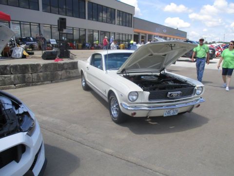 2004 Ford Crown Victoria - A classic white Ford Mustang is displayed with its hood open at an outdoor event.