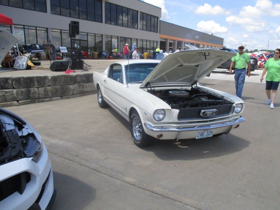 White 1965 Ford Mustang coupe with hood open, parked on pavement