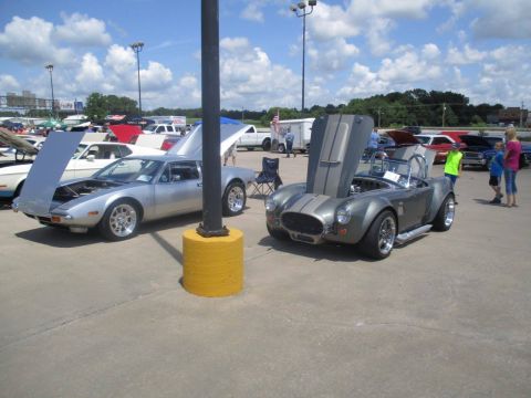 2004 Ford Crown Victoria - A gray convertible with racing stripes is parked with its hood open at an outdoor car show.