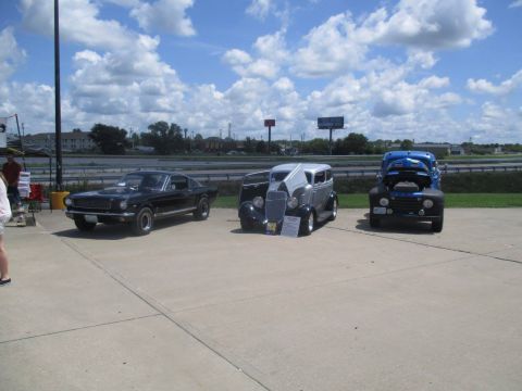 2004 Ford Crown Victoria - Three vintage vehicles displayed outdoors under a cloudy sky.