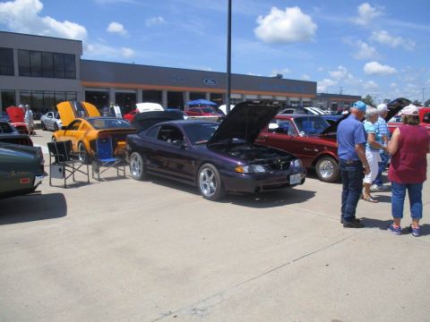 2004 Ford Crown Victoria - A purple 1994 Ford Mustang is displayed with its hood open at a car show, alongside other vehicles.