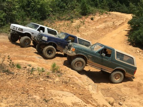 1989 Ford Bronco - Three Ford Broncos navigate a challenging off-road trail, their capabilities.