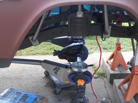 1972 Ford Bronco - The underside of a vehicle is shown with its rear axle assembly being serviced, supported by mechanical jacks and safety stands.