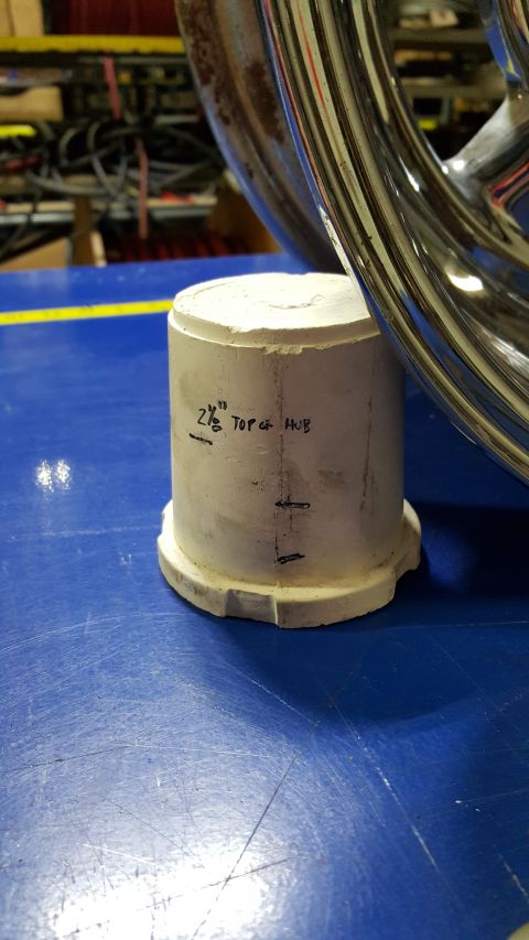 1973 Ford F-100 - A white cylindrical object with markings that read "2 1/8" TOP of HUB" sits on a blue surface next to a chrome wheel rim. The object appear…