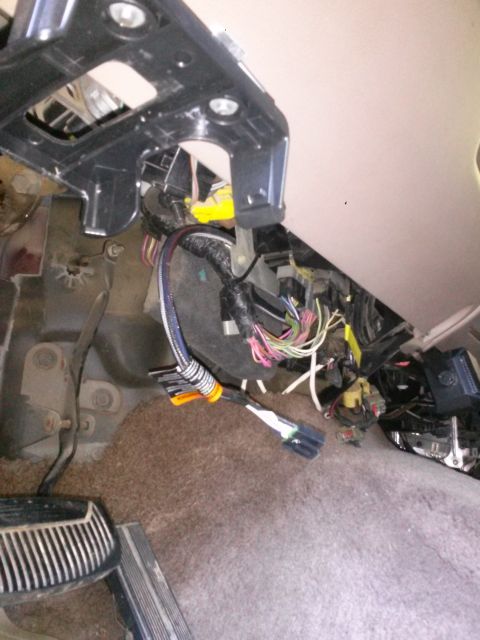 1996 Ford Bronco - The image shows a close-up view of the driver's side footwell of a vehicle, focusing on the wiring harness and pedals. Various wires, conne…