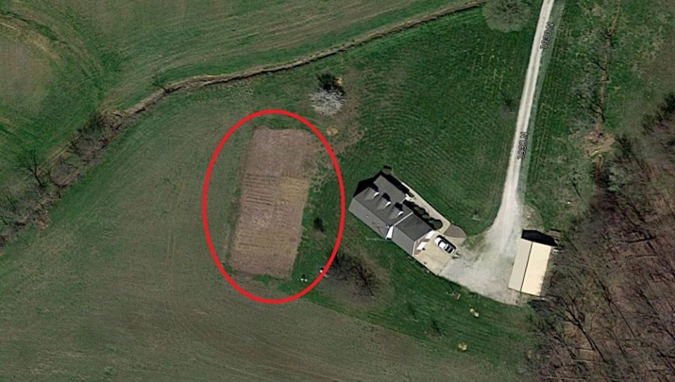 Aerial view of a rural property with a house and a tilled field.