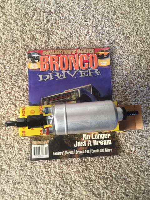 1982 Ford Bronco - A silver fuel pump is laid across two magazines, one titled "Bronco Driver" and the other "No Longer Just A Dream". The fuel pump has black…