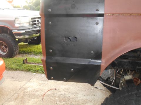 1972 Ford Bronco - A close-up view of the driver's side rear fender area of a vehicle undergoing modification, showing a black metal panel bolted over the ori…