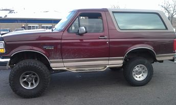 1996 Ford Bronco - The side view of a maroon 1996 Ford Bronco with a tan top and running boards is shown. It is lifted with large off-road tires and parked ou…