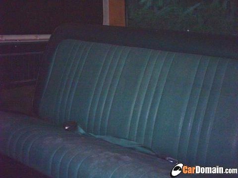 1978 Ford Bronco - The interior of a vehicle shows a teal bench seat with a seatbelt.