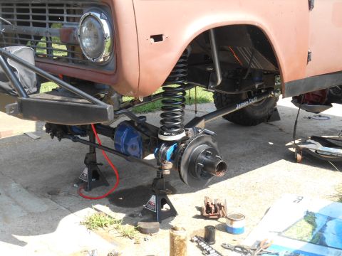 1972 Ford Bronco - The front suspension and undercarriage of a classic Ford Bronco is shown, lifted on jack stands. Modifications to the suspension, including…