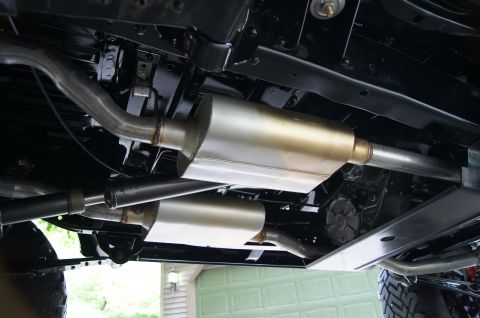 1979 Ford Bronco - Underside view of a vehicle's exhaust system, featuring dual mufflers and polished stainless steel piping, mounted to a black painted frame.