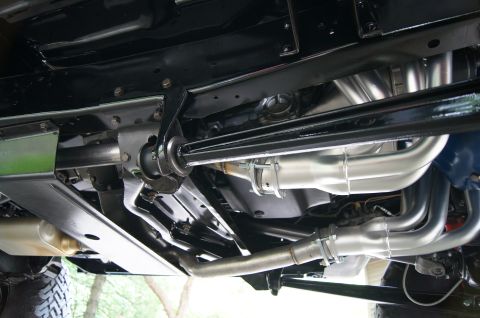 1979 Ford Bronco - The underside of a vehicle shows a custom exhaust system with shiny headers and pipes, connected to mufflers and the frame. The vehicle app…