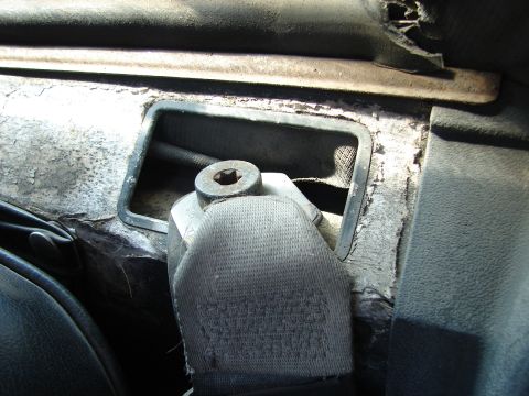 1973 Ford Ranchero - Close-up interior shot of a car's seatbelt mechanism and a vent opening. The surrounding area shows wear and tear with peeling material.