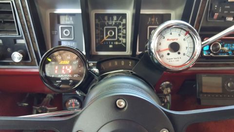1978 Ford Bronco - The interior of a classic vehicle shows a steering wheel with two gauges mounted to it. The left gauge displays an air/fuel ratio of 11.4,…
