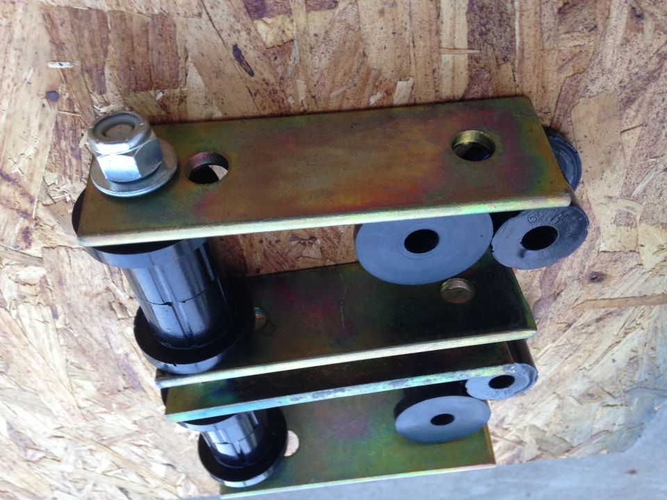 Suspension lift kit part with metal brackets and black bushings on wood